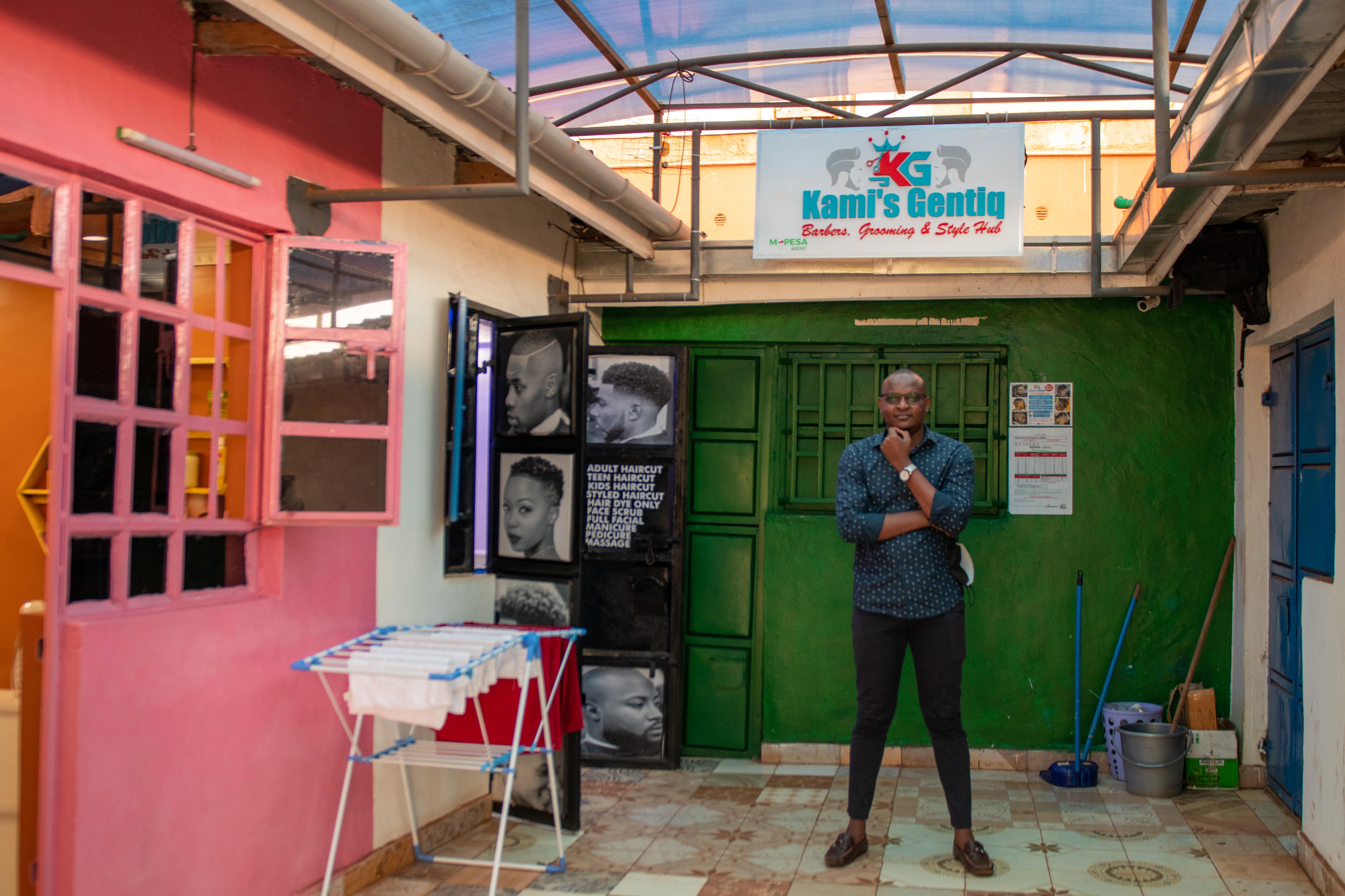 Kevin Sanya stands in front of his barber shop KG Barbers. Copyright: WIDU.africa