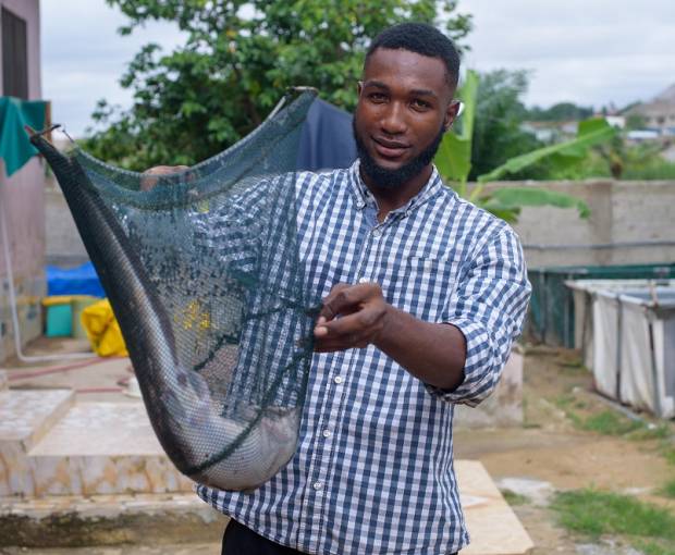 Ebenezer Paul Mensah presents a catfish from his aquaculture