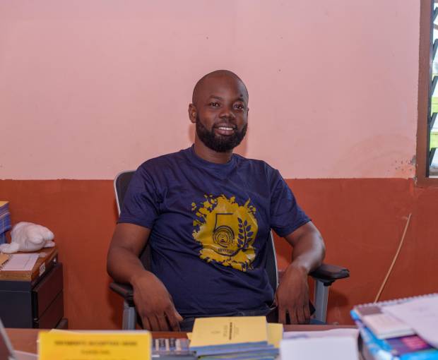Headmaster of Discovery Bay International School Kingsley Dzidzor Afetorgbor sits in his office and smiles into the camera