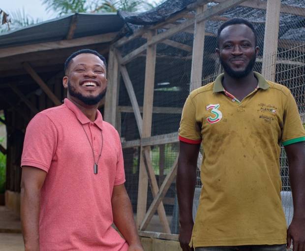 Kwasi and his employee stand in front of his Infinity Farm building