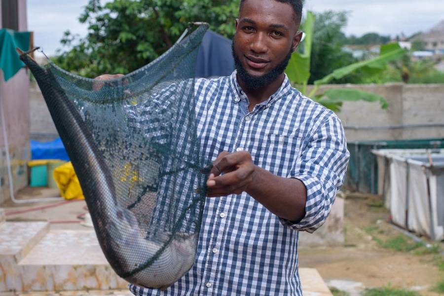 Ebenezer Paul Mensah presents a catfish from his aquaculture