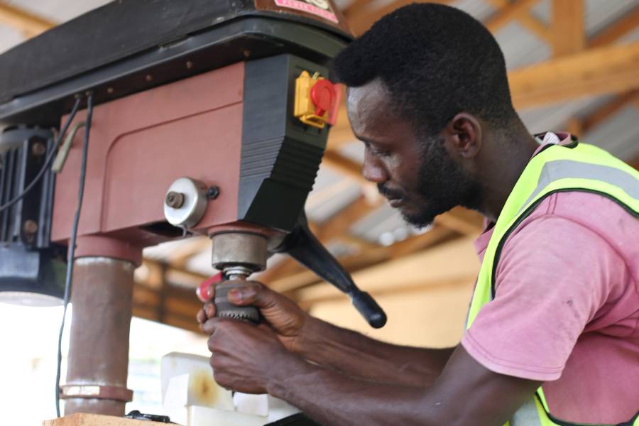 Stephen Orlando Mensah bedient eine Bohrer in seiner Werkstatt. 