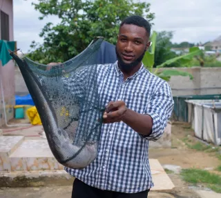 Ebenezer Paul Mensah presents a catfish from his aquaculture