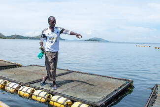 Employee of a WIDU participant from Kenya feeds fish in a aquaculture