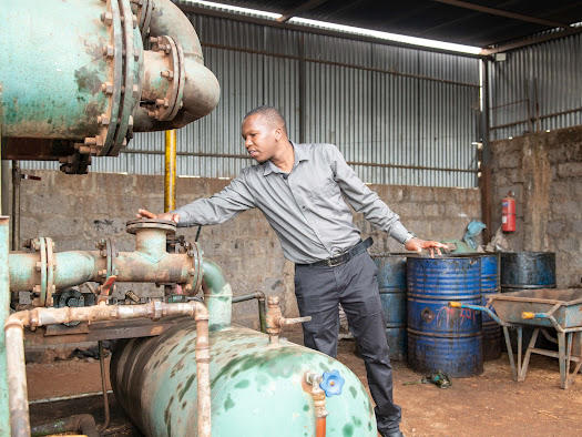 Entpreneur leans over to machine to check whether it works