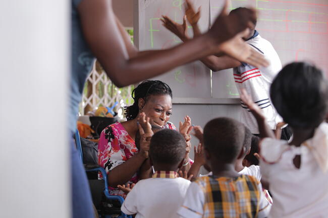 Ghanaian kinder garden teacher who uses a wheelchair plays with her class