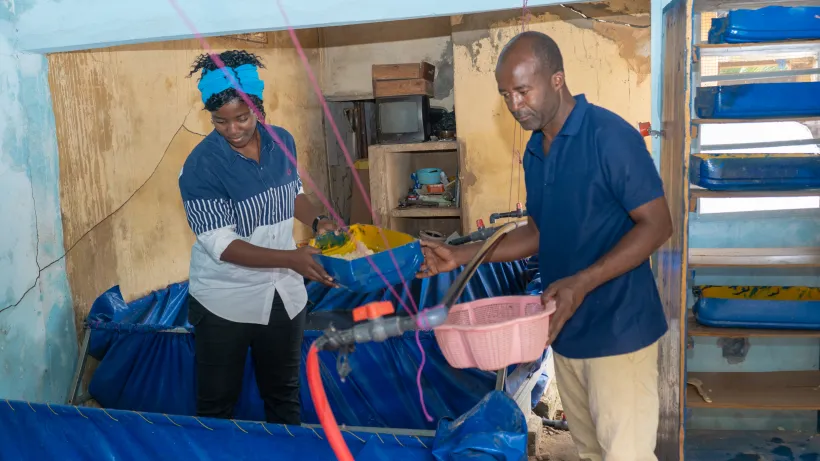 Kanlé Lionèle and her colleague feed their fish farm 