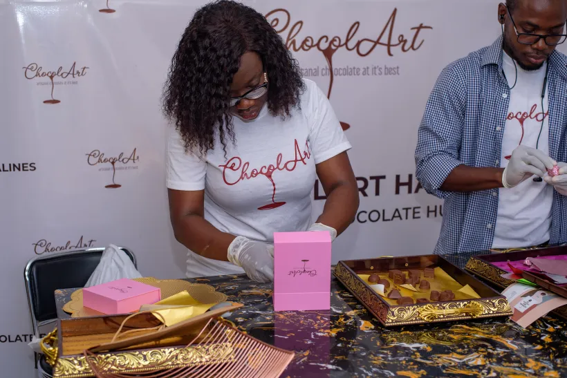 Pearl Kitcher and a team member carefully packaging handcrafted chocolates during a production session.