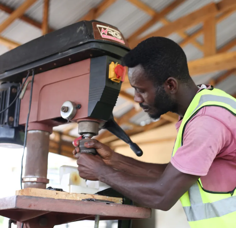 Stephen Orlando Mensah utilise une perceuse dans son atelier.