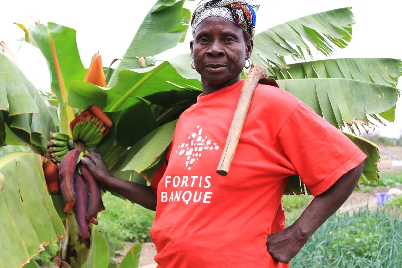 Farmer standing next to a palm tree and presenting his harvest. ©GIZ